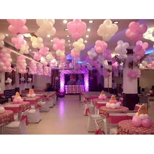 A birthday party venue decorated with pink balloons and a lit stage